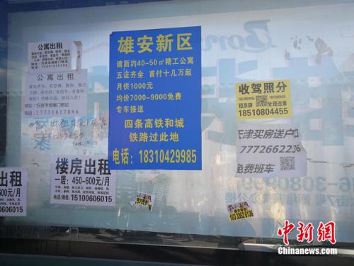 街道公交站牌旁边的综合宣传栏里贴着雄安新区的广告。中新网记者 邱宇 摄