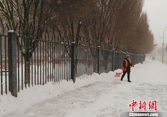 环卫工人清扫人行道上积雪。　戚亚平 摄
