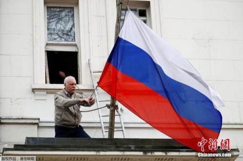 当地时间2018年3月14日，一名男子将俄罗斯驻英国大使馆门前的俄罗斯国旗取下。